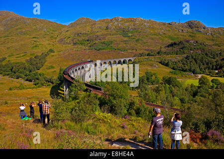 tourists photograph the Jacobite Steam train on Glenfinnan Viaduct, traveling from Mallaig to Fort William  Lochaber Scotland Stock Photo