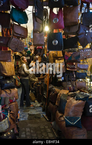 Vertical portrait of a Western tourist being served in a leather hangbag shop in the souks of Marrakech. Stock Photo