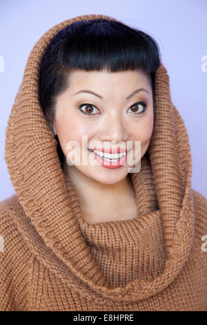 Asian woman with warm fuzzy cowl neck sweater on. Short hair cut with cute bangs. Stock Photo