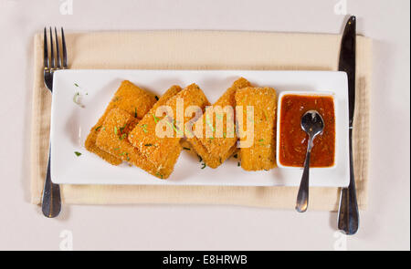 Crispy Appetizing Main Dish with Hot Dipping Sauce on White Rectangular Plate. Served with Fork and Knife on White Table. Stock Photo