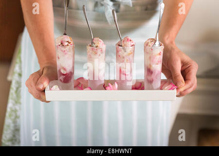 raspberry ripple ice cream in shot glasses held in hands on tray Stock Photo