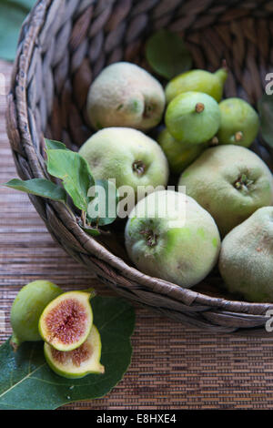 quinces and figs in woven basket with cut figs in foreground Stock Photo