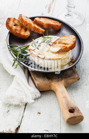 Baked Camembert cheese with toasted bread on cast-iron frying pan Stock Photo