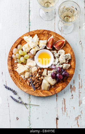 Cheese plate and wine Assortment of various types of cheese on olive wood plate Stock Photo