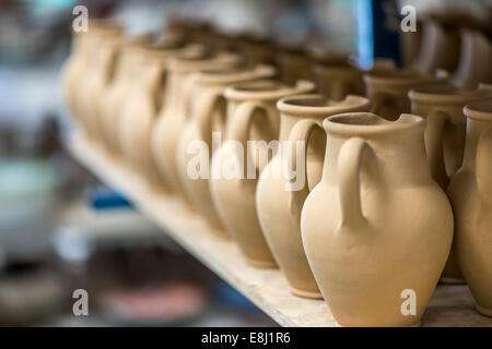 Ceramic dishware arranged on shelf in pottery workshop Stock Photo