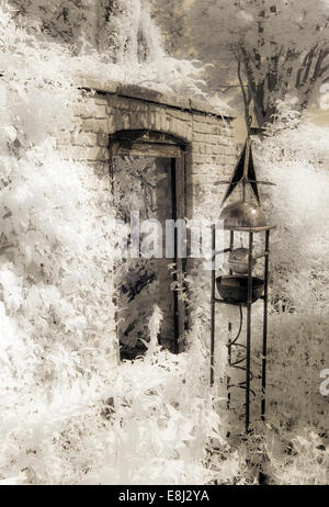 Infrared photograph of a classic English garden, brickwall with open doorway, ornate obelisk at Wollerton Old Hall (NGS) Stock Photo