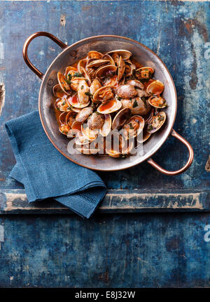 Shells vongole with parsley and tomato sauce on blue background Stock Photo