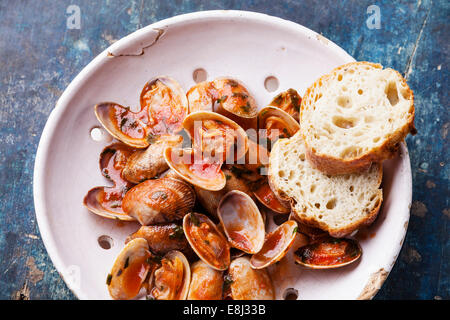 Shells vongole with parsley and tomato sauce in vintage ceramic colander on blue background Stock Photo