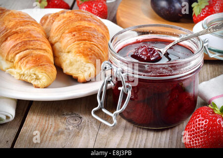 Strawberry jam and croissant on wooden table. Stock Photo