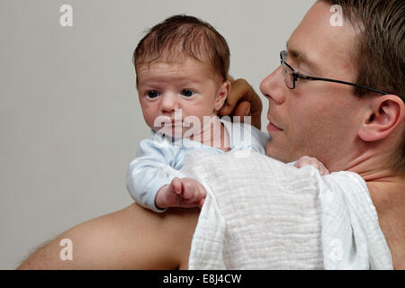 Three-week-old infant boy being held over his shoulder by his father, with burp cloth Stock Photo