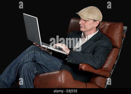 Man sitting indoors using laptop on Black background - clipping path Stock Photo