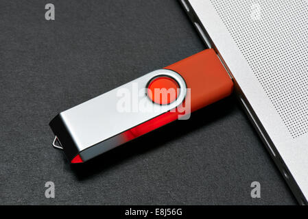 Flash memory drive plugged into a laptop port on black table Stock Photo