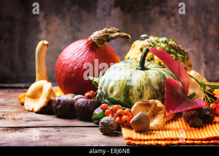 Pumpkins, nuts, berries and mushrooms chanterelle over old wooden table. Stock Photo