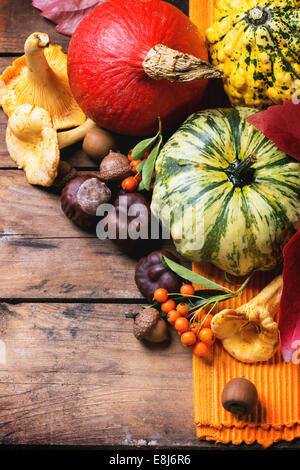 Pumpkins, nuts, berries and mushrooms chanterelle over old wooden table. Stock Photo