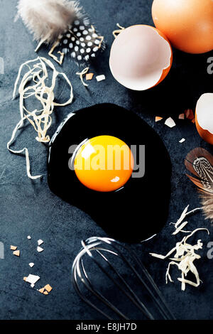 Fresh eggs with straw and  feathers  on a dark background