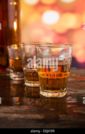 glass of rum whiskey over defocused lights background Stock Photo