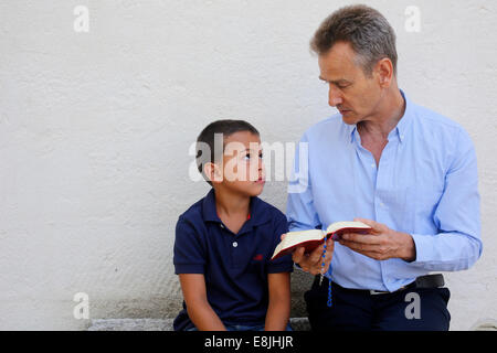 Father reading the Bible to his son Stock Photo