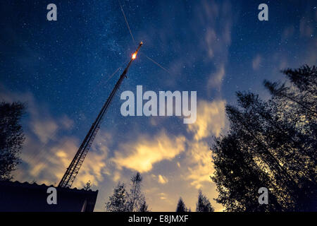 A telecommunication link tower with a blinking light. Night sky with stars on the background. Stock Photo