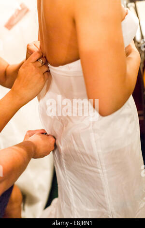 Bride dressing up for her wedding dress with help of brides maids. Stock Photo
