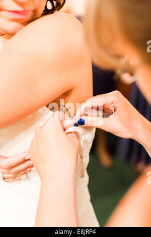 Bride dressing up for her wedding dress with help of brides maids. Stock Photo