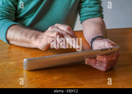 Male working with a digital tablet at home on the table Stock Photo