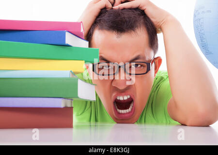 boring and tired young man with many books on the desk Stock Photo