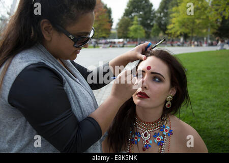 Asian model has her make up done my a make up artist prior to a photo shoot at Jubilee Gardens. The South Bank, London, UK. Stock Photo