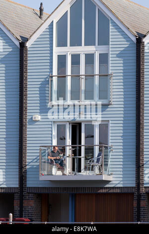 Man reading on the balcony of a canalside apartment, Chichester, West Sussex Stock Photo