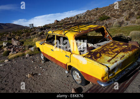 Abandoned yellow car rusting outside village in mountains, Chile Stock Photo