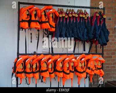 Two rails of colourful inflatable life jackets in a boatyard in Henley On Thames Stock Photo