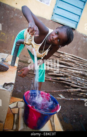 Girl filling bucket from water faucet, Kroo Bay, Freetown, Sierra Leone. Photo © Nile Sprague Stock Photo