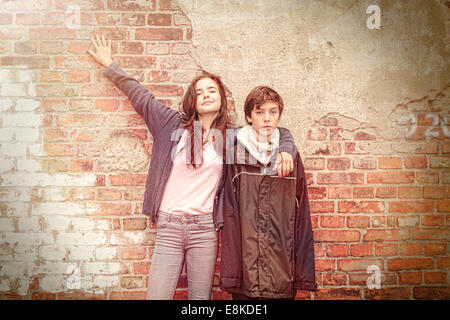 siblings in front of an old grungy brick wall Stock Photo