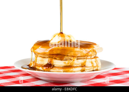 Sweet maple syrup being poured over a hot, freshly buttered stack of pancakes. Stock Photo