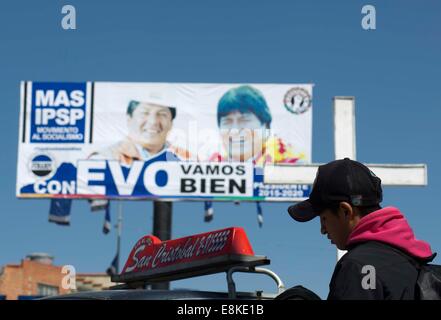 El Alto, Bolivia. 9th Oct, 2014. A man stands in front of a campaign poster in El Alto City, western Bolivia, on Oct. 9, 2014. The Bolivian general elections will be held on Oct. 12. © David de la Paz/Xinhua/Alamy Live News Stock Photo