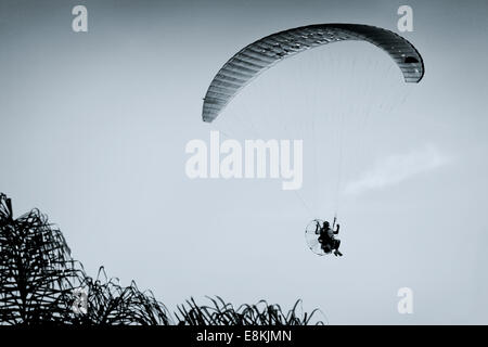 A powered paraglider pilot in flight with a blue clean sky in the background Stock Photo