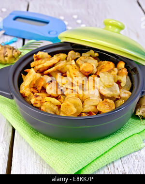 Jerusalem artichokes roasted in a roasting pan with a lid, fresh tubers on a napkin, the meter and pills on a white background w Stock Photo