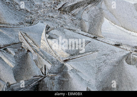 Ice frost etched on vehicle window screen with pale sun bleached behind. Organic, natural swirls and crystaline formations Stock Photo