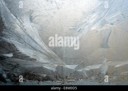 Ice frost etched on vehicle window screen with pale sun bleached behind. Organic, natural swirls and crystaline formations Stock Photo