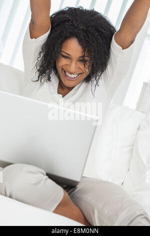 Beautiful African American woman happy and surprised successful celebration using her laptop computer Stock Photo