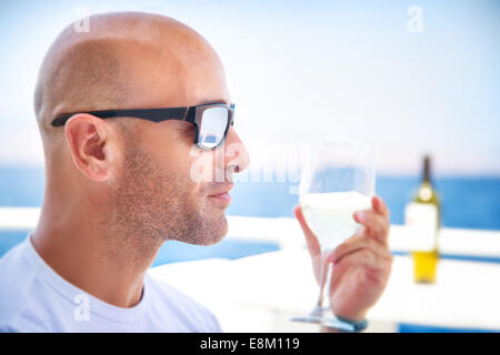Closeup portrait of handsome man drinking wine in outdoors restaurant on luxury yacht, tasting luxury alcohol beverage Stock Photo