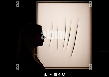 London, UK. 10th October, 2014. Sotheby’s assistants look at ‘Concetto Spaziale, Attese 1964’ by Lucio Fontana (Est. $2.2-2.8 million) during the press view of the Frieze week auction press view at Sotheby’s London. Credit:  Piero Cruciatti/Alamy Live News Stock Photo