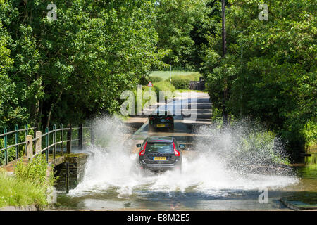 Vehicle driving through a stream. A car splashing water when driven through the ford crossing the road at Rufford, Nottinghamshire, England, UK Stock Photo