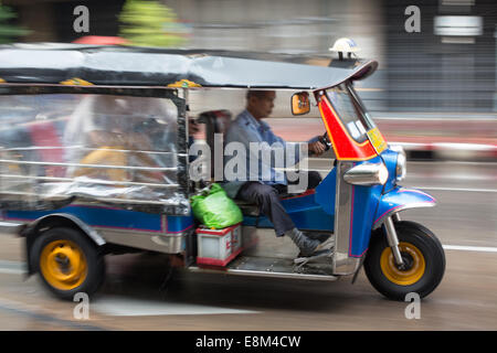 Tuk-tuk in blurred motion drives through a rainy Chinatown street, Bangkok, Thailand. Stock Photo