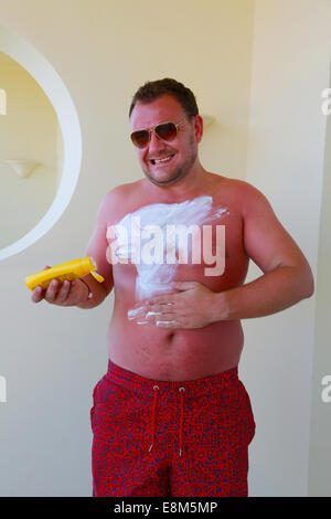 Very sun burnt man applying cream Stock Photo