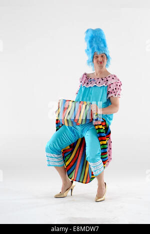 Man in fancy dress comedy costume as one of the ugly sisters outfit from Cinderella pantomime, with colourful dress and blue wig Stock Photo