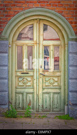 A grungy artistic image of an old ornate rustic doorway that has fallen into disrepair with faded, peeling green paint. Stock Photo