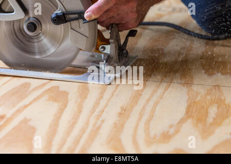Man using a circular saw to cut plywood Stock Photo