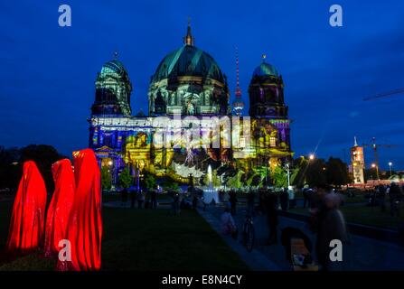 Berlin, Germany. 10th Oct, 2014. The work of art 'Die Waechter der Zeit' (The guardians of time) stands in front of the illuminated Berlin Cathedral during the 'Festival of Lights' in Berlin, Germany, 10 October 2014. Numerous buildings and sights in the capital will be illuminated until 19 October 2014. Photo: Paul Zinken/dpa/Alamy Live News Stock Photo