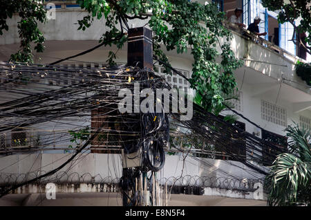 Pole with a tangle of electrical and telephone cables in city center Stock Photo