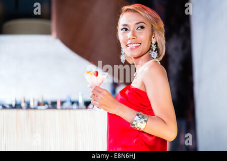 Asian woman drinking cocktails in fancy bar or club Stock Photo